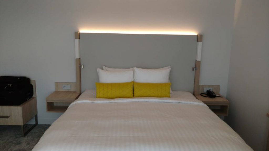 a bed with a white blanket and yellow pillows